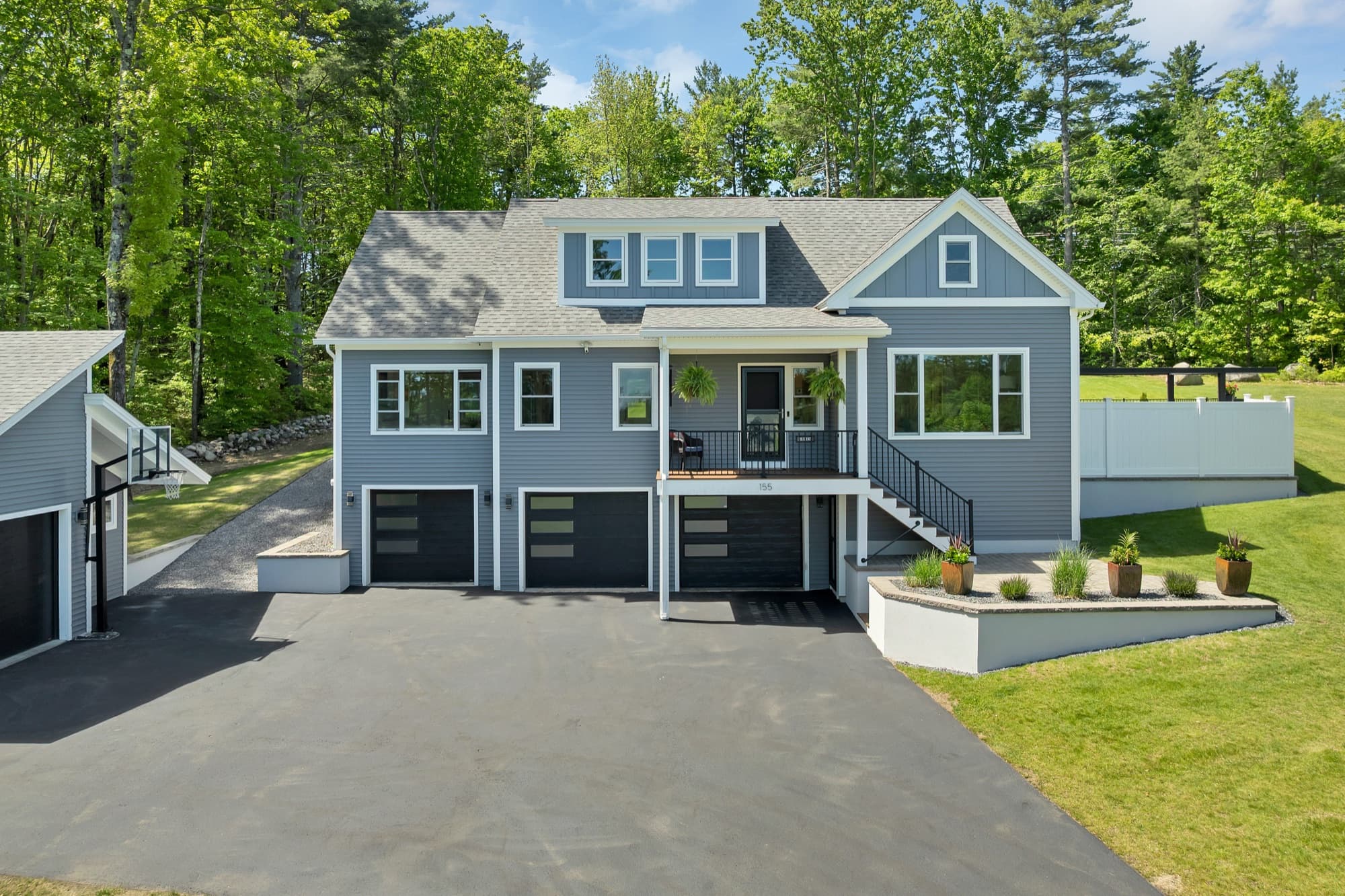 Front exterior of the dark-blue modern bungalow with attached three-car garage